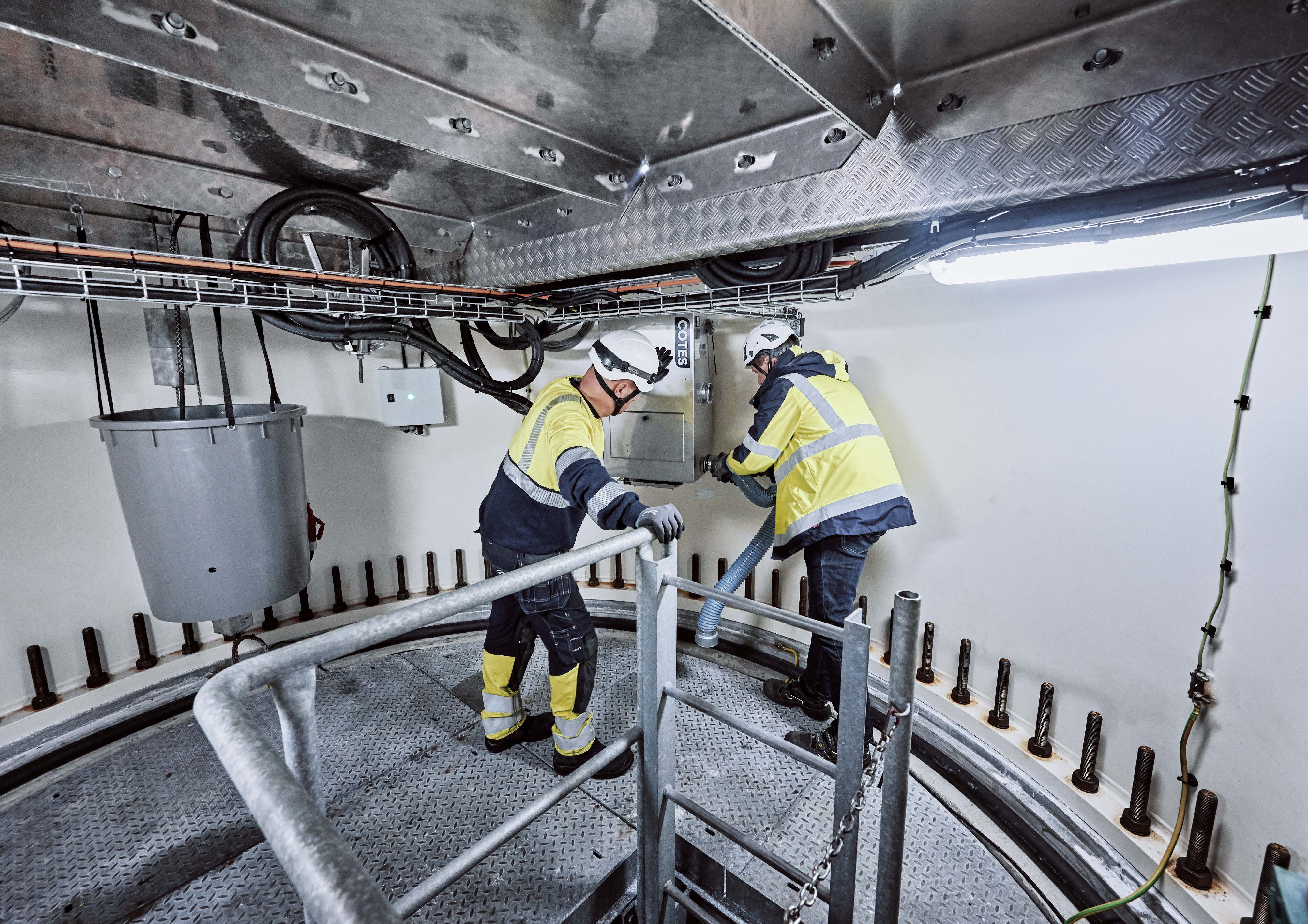 Two technicians installing a Cotes CWO adsorption dehumidifier in a retrofit solution in an offshore wind turbine