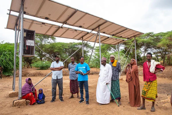 People standing under a solar panel in Kenya